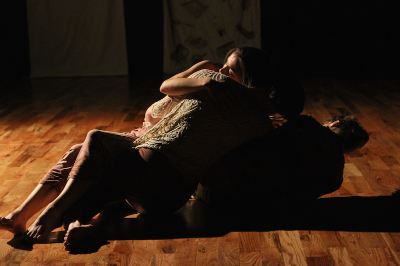 The three dancers are entangled on the floor in shadow